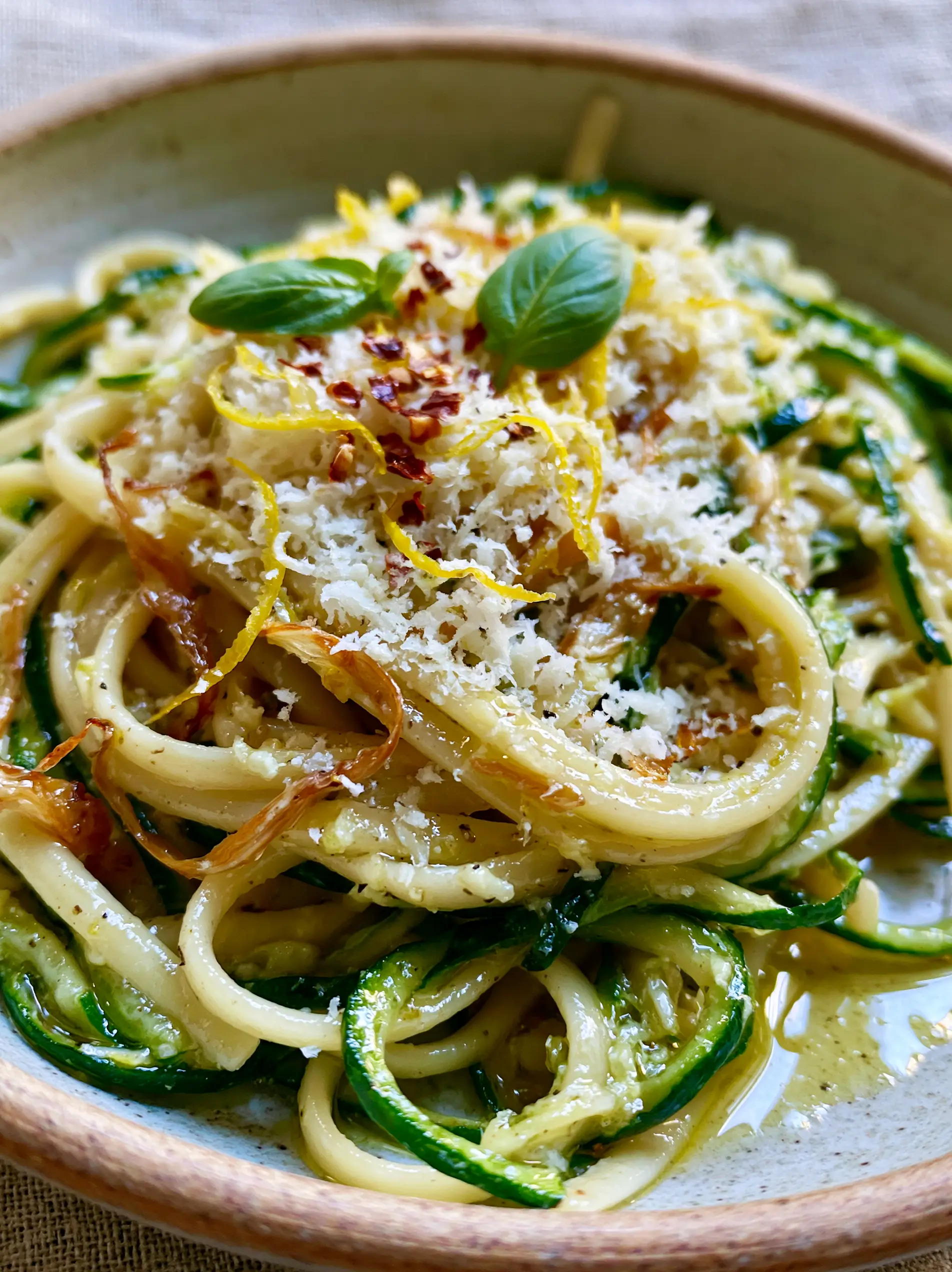 Extreme close-up of glossy lemon butter sauce on linguine with golden garlic and zucchini. (Summer Pasta Recipe)